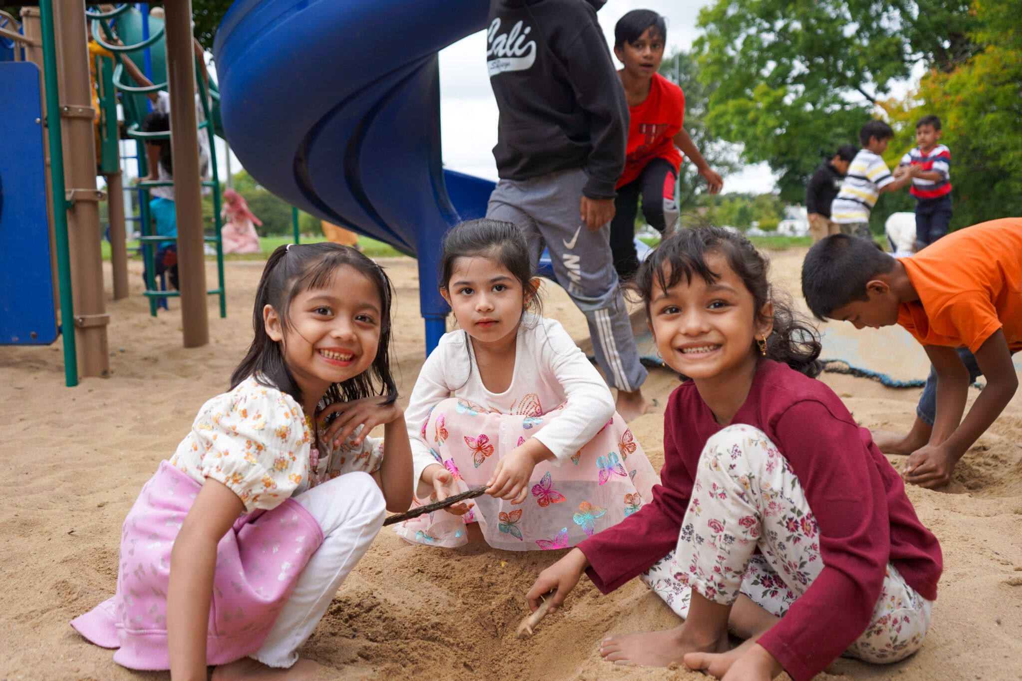 image of three young girls playing in sandbox together