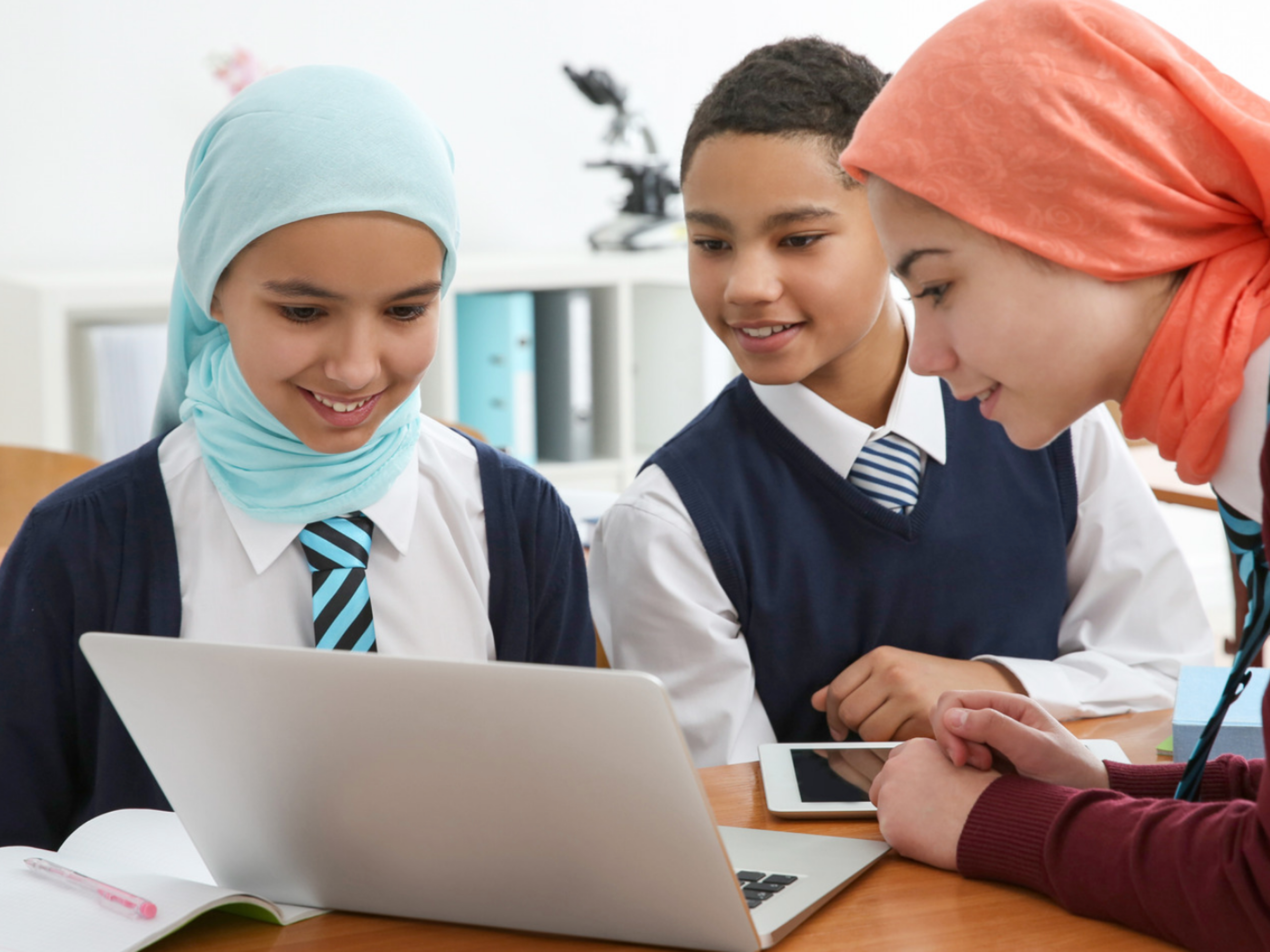 image of three teens surrounding laptop